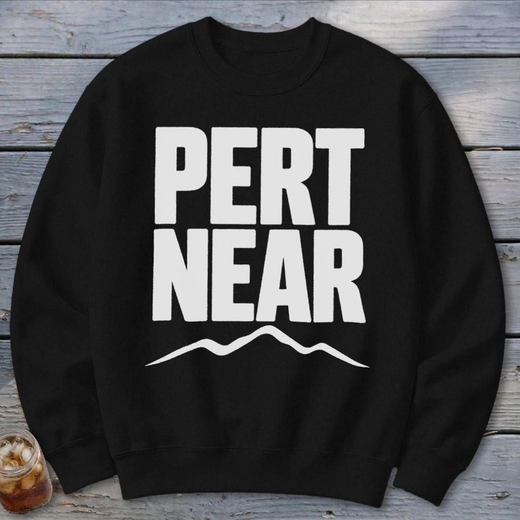 A black crewneck sweatshirt with white text reading "PERT NEAR" and a mountain graphic below.