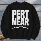 A black crewneck sweatshirt with white text reading "PERT NEAR" and a mountain graphic below.