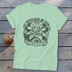 T-shirt graphic of hands sewing a quilt, with text "Stitched by Kin Every Square Tells a Story".