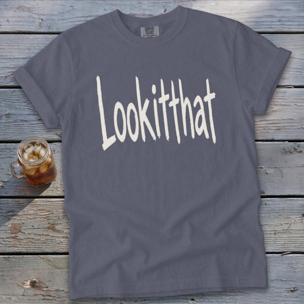 Slate gray t-shirt with "Lookitthat" text, on a wooden surface.