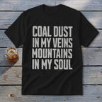 A black t-shirt with white distressed text that reads COAL DUST IN MY VEINS MOUNTAINS IN MY SOUL.