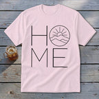 Light pink t-shirt displaying a black line art graphic of mountains and sun substituting for the letter O in the word HOME.