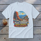 T-shirt graphic with mountains, road, and text "Peak weekend. Same playlist. New overlook."
