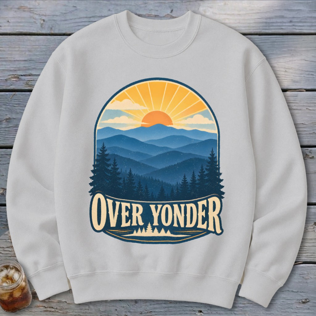 Light grey crewneck sweatshirt featuring a graphic of blue mountain ranges, pine trees, and a setting sun with the text Over Yonder.