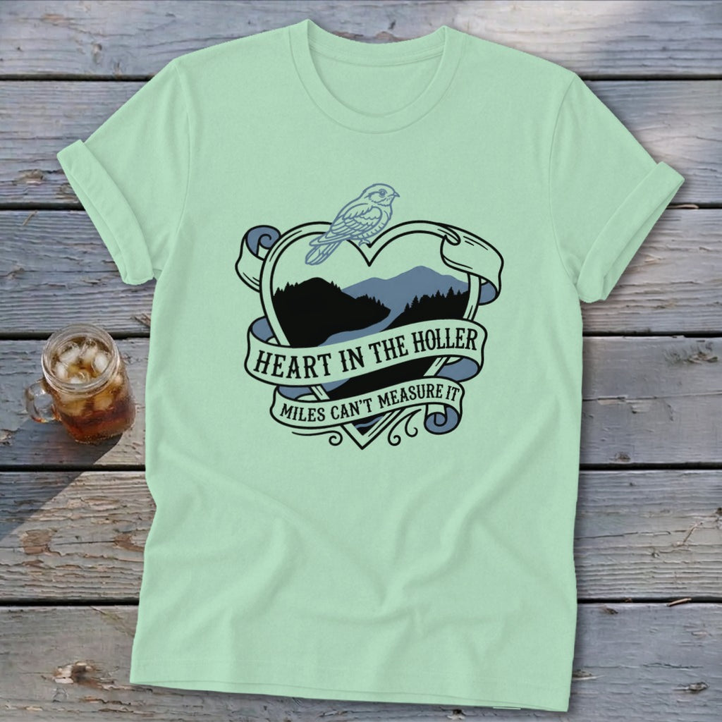 Light green t-shirt with heart design, mountains, bird, and text "Heart in the Holler".
