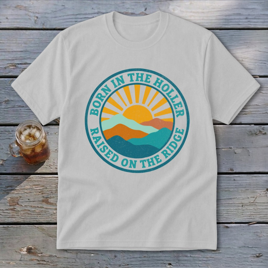 Light gray crewneck t-shirt featuring a retro mountain and sun graphic with text reading BORN IN THE HOLLER RAISED ON THE RIDGE.