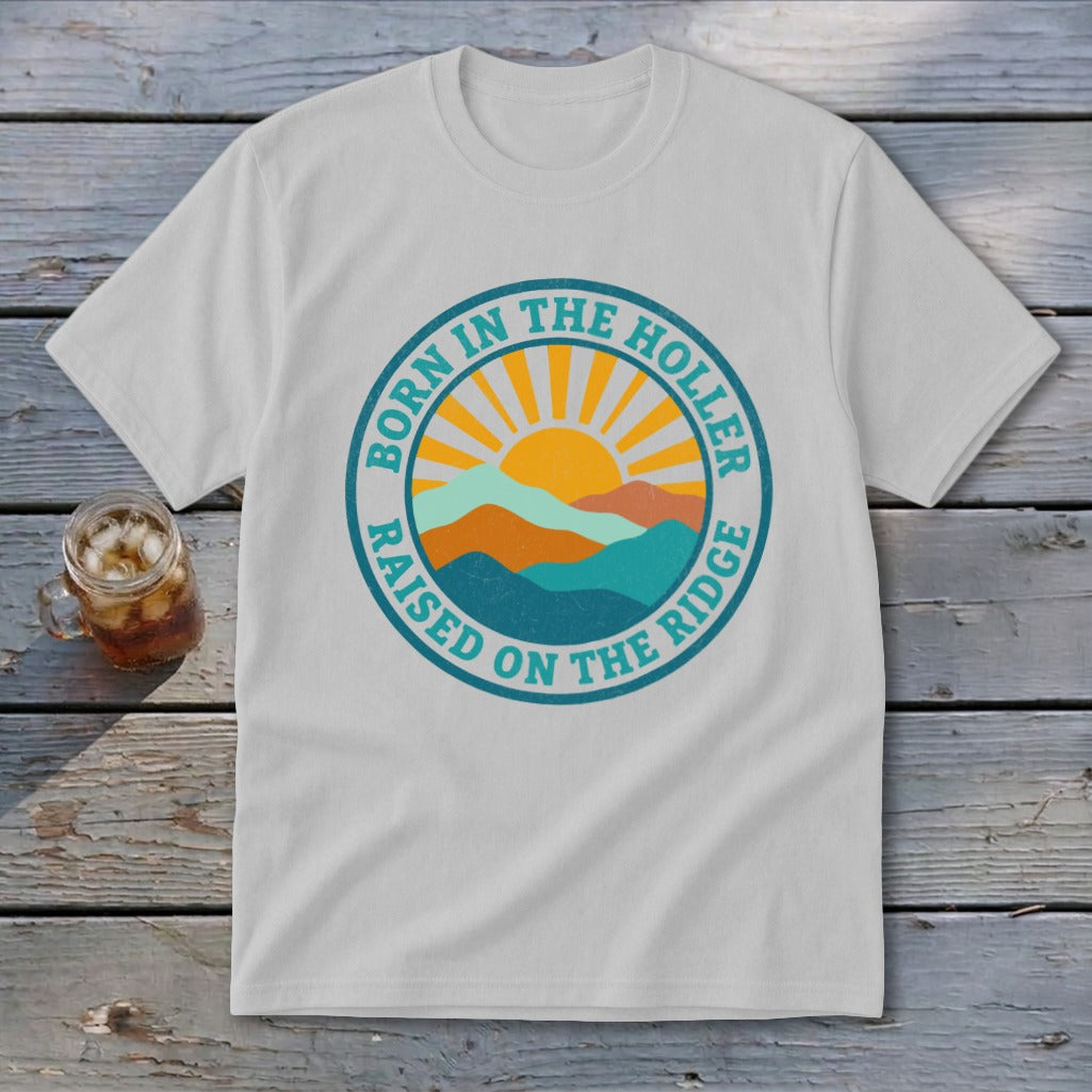 Light gray crewneck t-shirt featuring a retro mountain and sun graphic with text reading BORN IN THE HOLLER RAISED ON THE RIDGE.