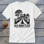 White t-shirt with black graphic of a farmhouse, trees, fence, and text "OLD HOME PLACE".