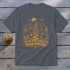 Dark gray t-shirt with orange mountain, lantern, and trail graphic with text.