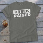 Gray t-shirt with white text that reads "CREEK RAISED" in a box.