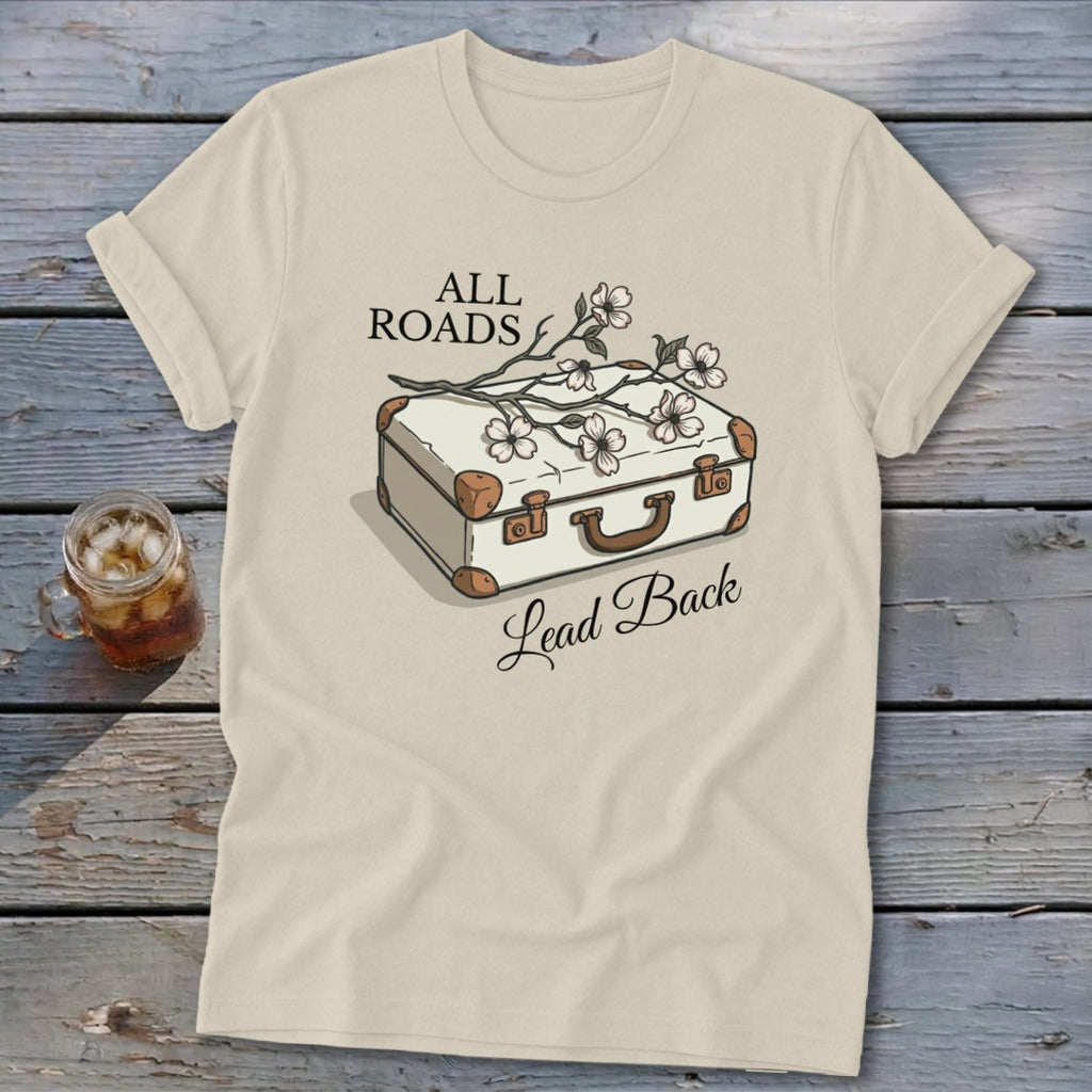 Cream t-shirt with illustration of suitcase and flowers, text "ALL ROADS Lead Back".