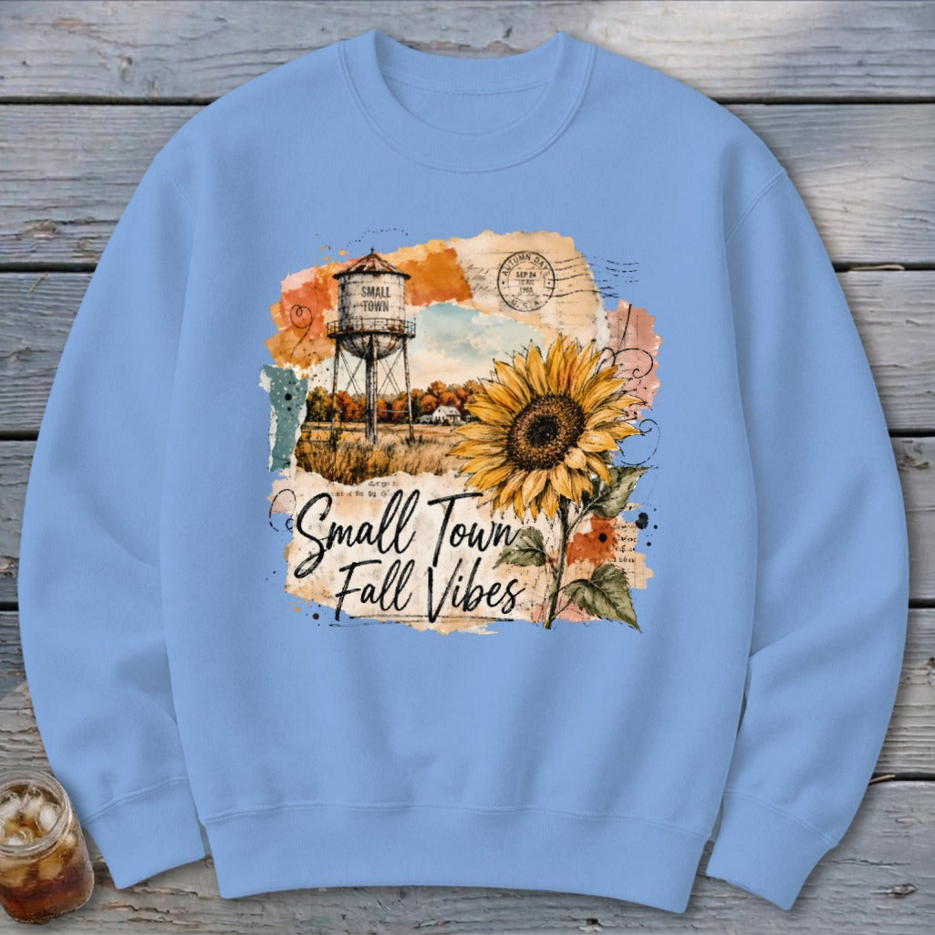 Light blue sweatshirt with "Small Town Fall Vibes" graphic and sunflower.