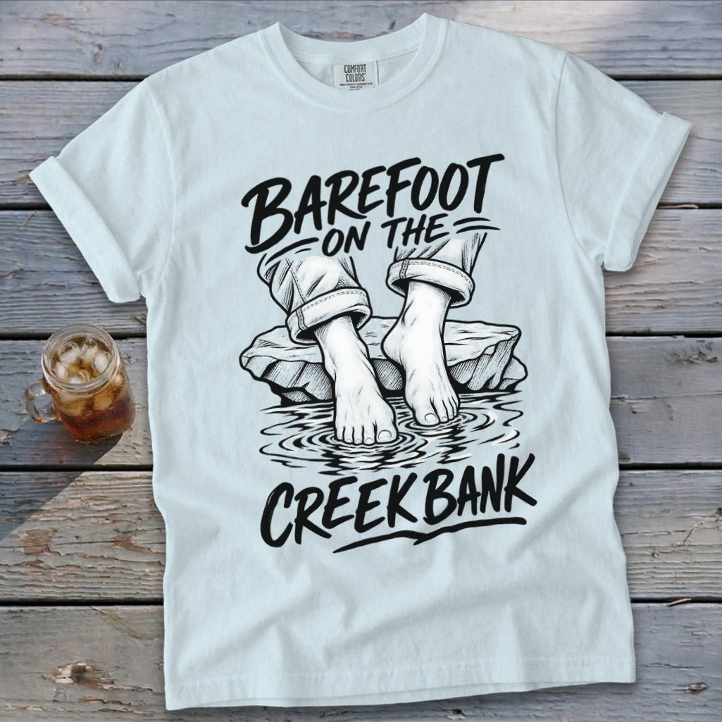 White t-shirt with "Barefoot on the Creek Bank" graphic of bare feet in water.