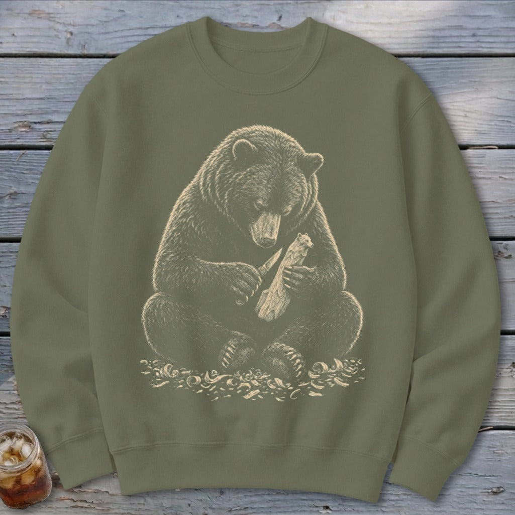 Brown bear carving wood with a knife on a green sweatshirt.