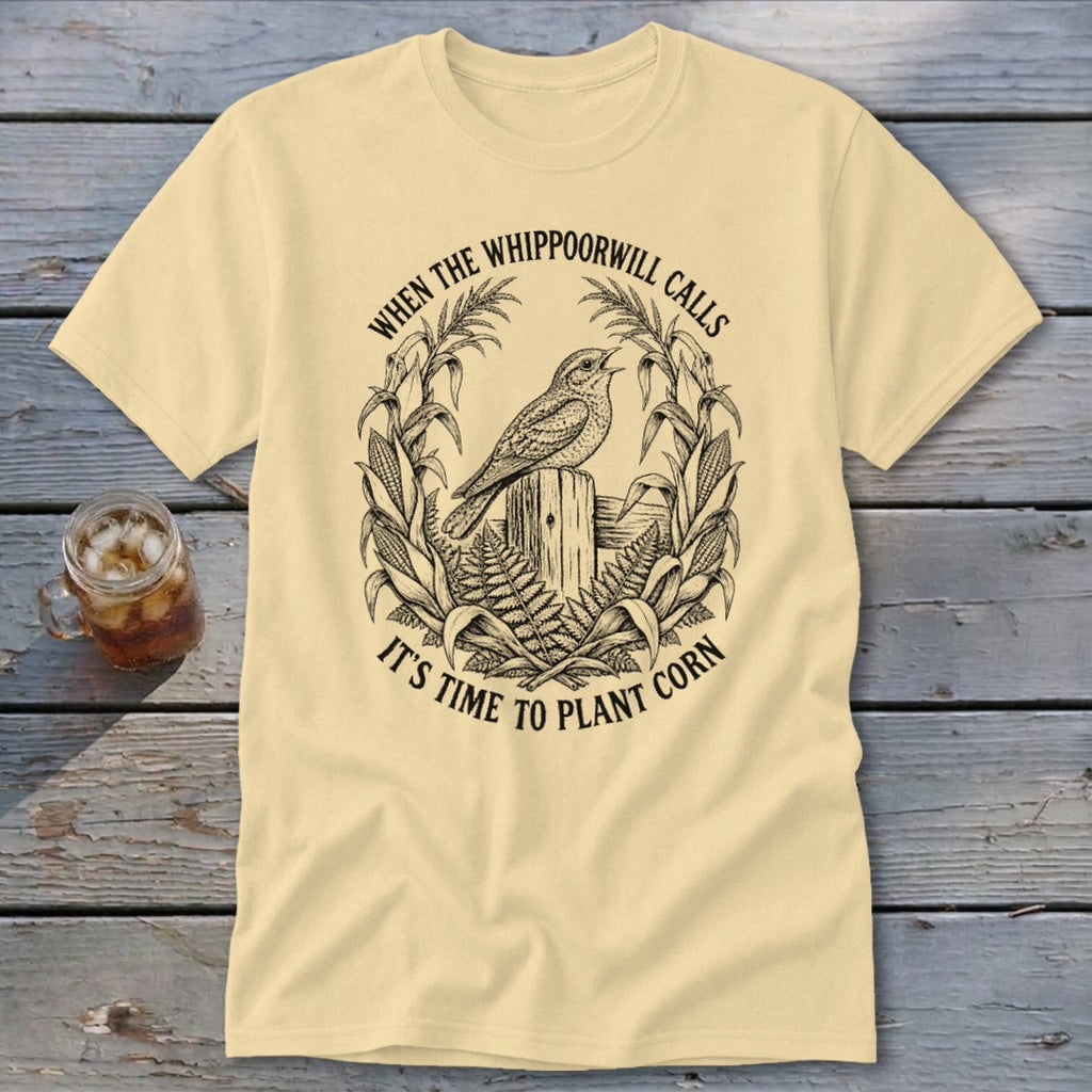 Cream-colored t-shirt with a black line art graphic of a bird on a fence post surrounded by corn.