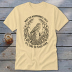 Cream-colored t-shirt with a black line art graphic of a bird on a fence post surrounded by corn.