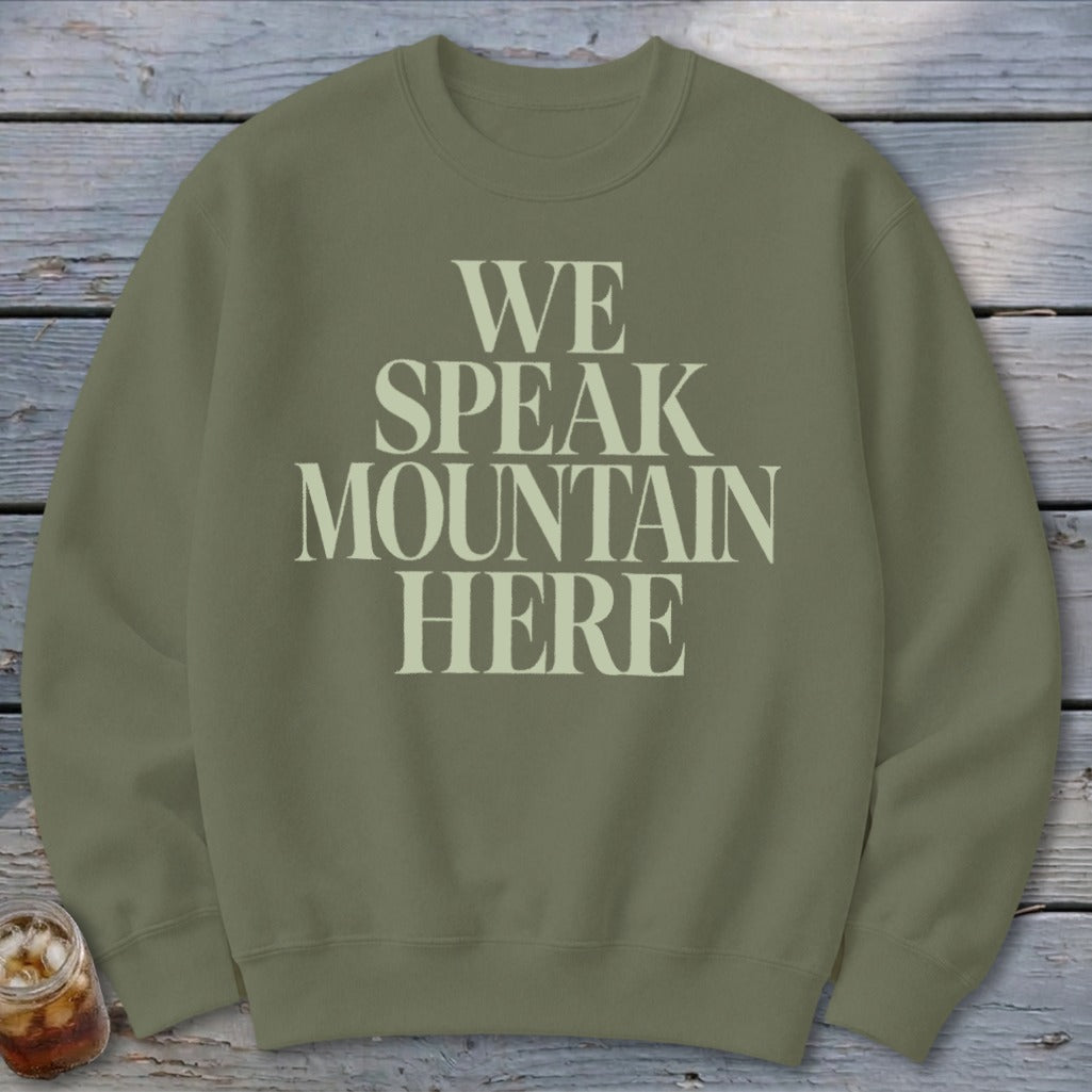 Olive green crewneck sweatshirt with "WE SPEAK MOUNTAIN HERE" printed in cream.