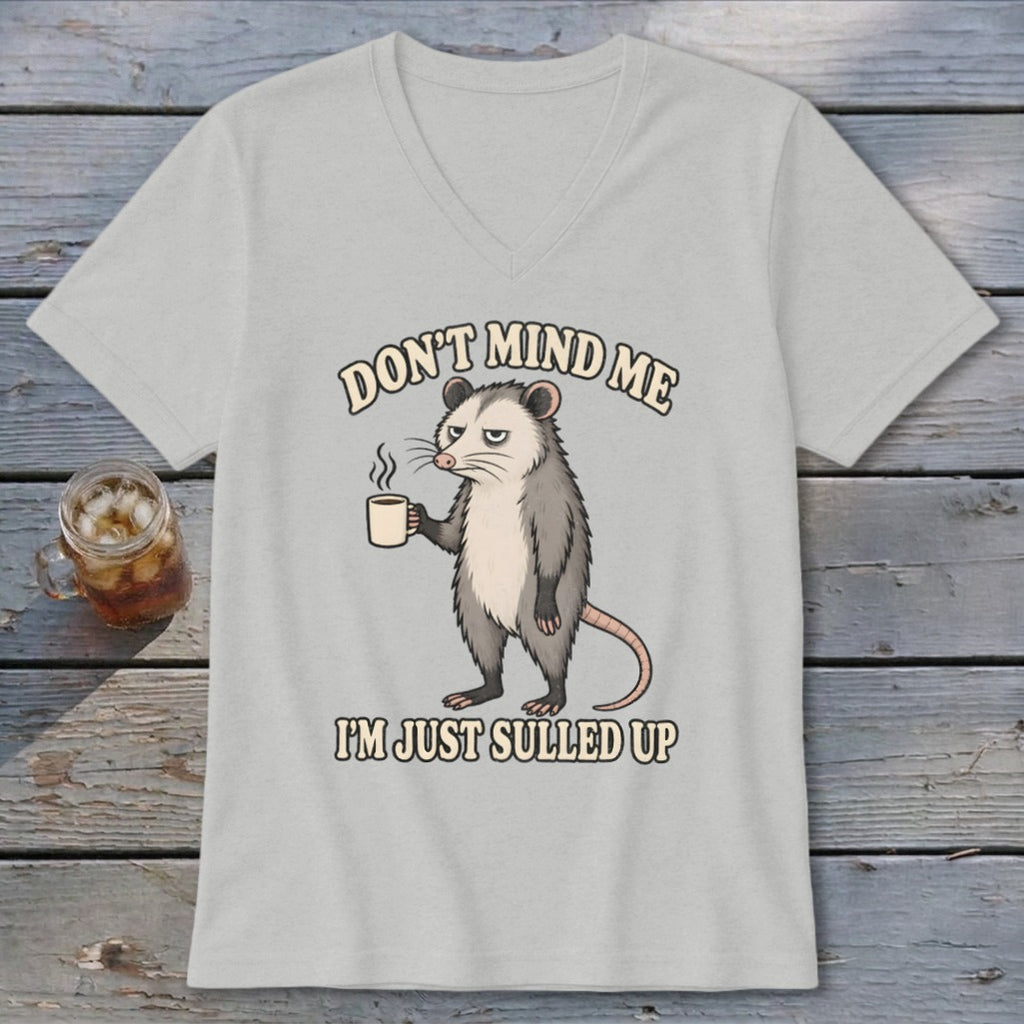 Light gray V-neck t-shirt featuring a graphic of an opossum holding a coffee mug with the text "DON'T MIND ME I'M JUST SULLED UP".