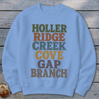 Light blue crewneck sweatshirt featuring stacked multi-colored text that reads HOLLER RIDGE CREEK COVE GAP BRANCH.