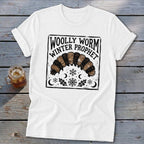 A white t-shirt featuring a black graphic of a woolly worm, snowflakes, moons, and text reading Woolly Worm Winter Prophet.