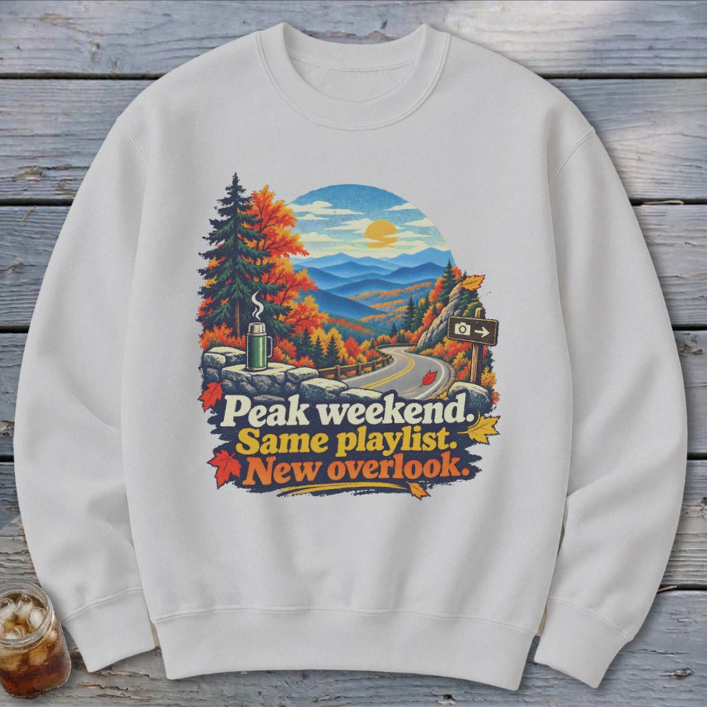 Sweatshirt with autumn mountain scene and text "Peak weekend. Same playlist. New overlook."
