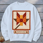 White sweatshirt with a quilted maple leaf design and "Maple Leaf" text.
