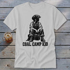 T-shirt with black graphic of a boy sitting with a bucket, text reads "COAL CAMP KID".