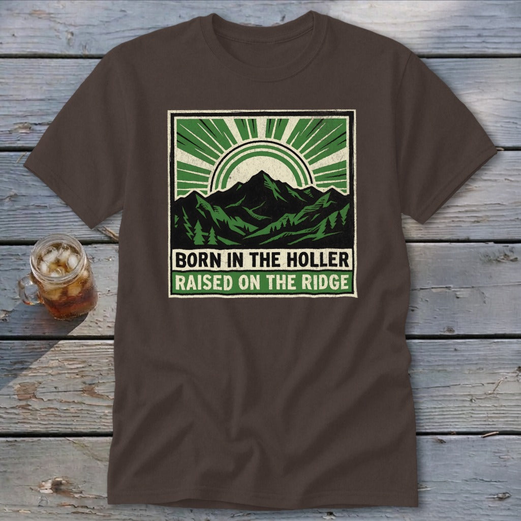 Brown t-shirt featuring a green graphic of mountains, trees, and text reading BORN IN THE HOLLER RAISED ON THE RIDGE.