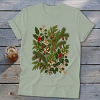 Light green t-shirt with a detailed botanical print of pine branches, holly, berries, and pinecones.
