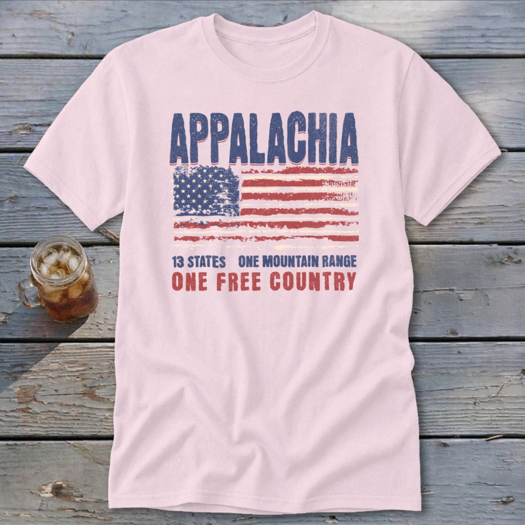 A light pink t-shirt featuring a distressed American flag graphic and text reading Appalachia, 13 States, One Mountain Range, One Free Country.