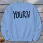 Light blue sweatshirt with navy text reading "YOUR'N" on the front.