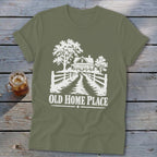 Olive green t-shirt with white graphic of a farmhouse, trees, and fence with text "OLD HOME PLACE".