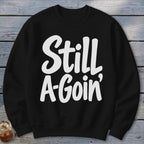 A black crewneck sweatshirt with the white text Still A-Goin centered on the chest.