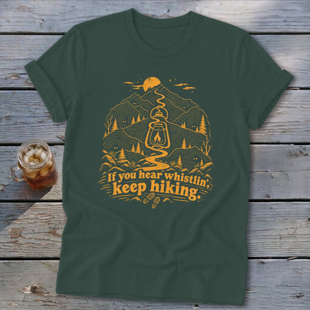 Dark green t-shirt with orange hiking graphic and text "If you hear whistlin, keep hiking."