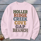 Light pink crewneck sweatshirt featuring stacked multi-colored text that reads HOLLER RIDGE CREEK COVE GAP BRANCH.