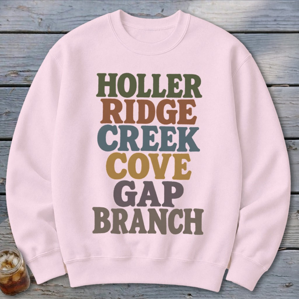 Light pink crewneck sweatshirt featuring stacked multi-colored text that reads HOLLER RIDGE CREEK COVE GAP BRANCH.