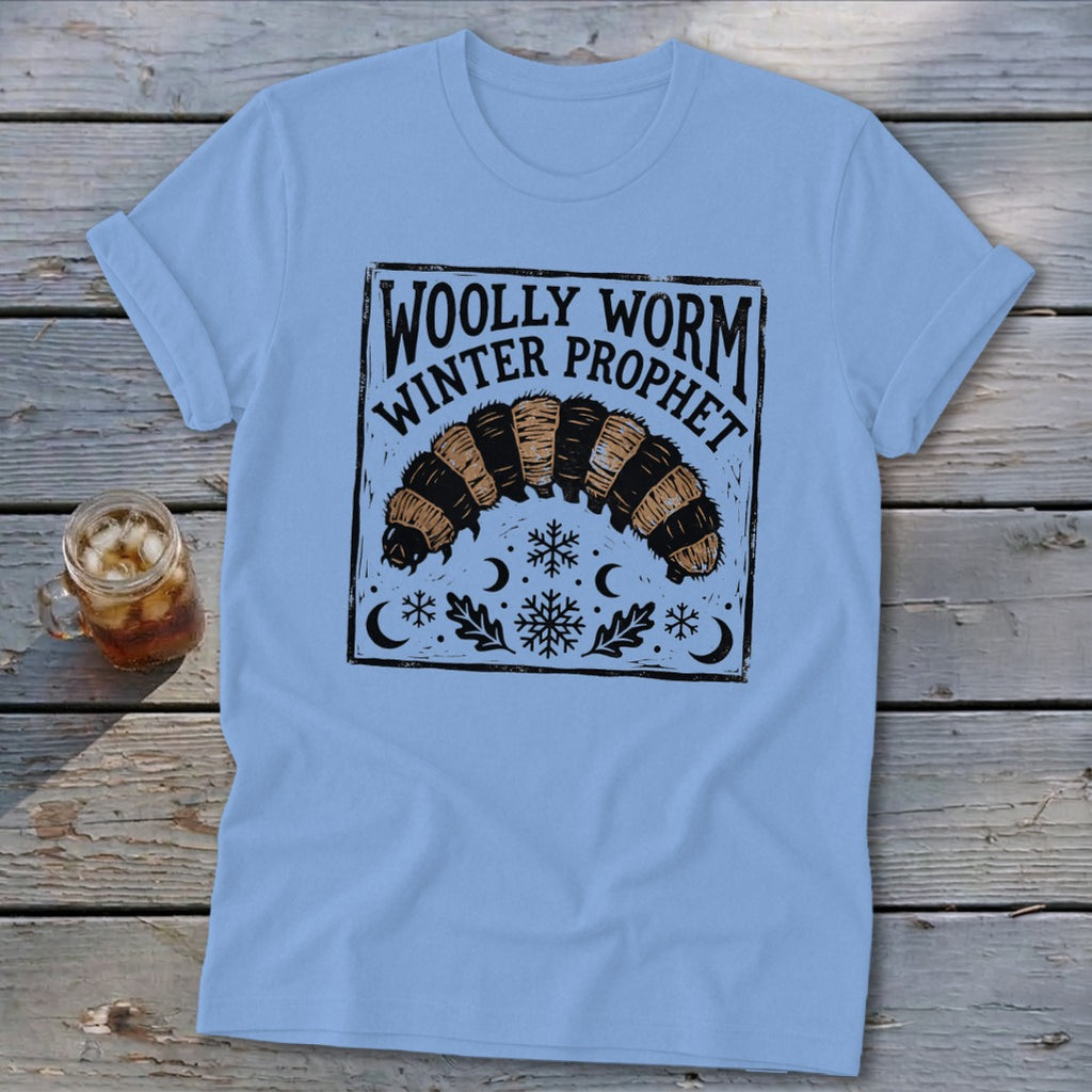 Light blue t-shirt featuring a graphic of a woolly worm caterpillar with text that reads WOLLY WORM WINTER PROPHET.