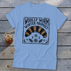 Light blue t-shirt featuring a graphic of a woolly worm caterpillar with text that reads WOLLY WORM WINTER PROPHET.