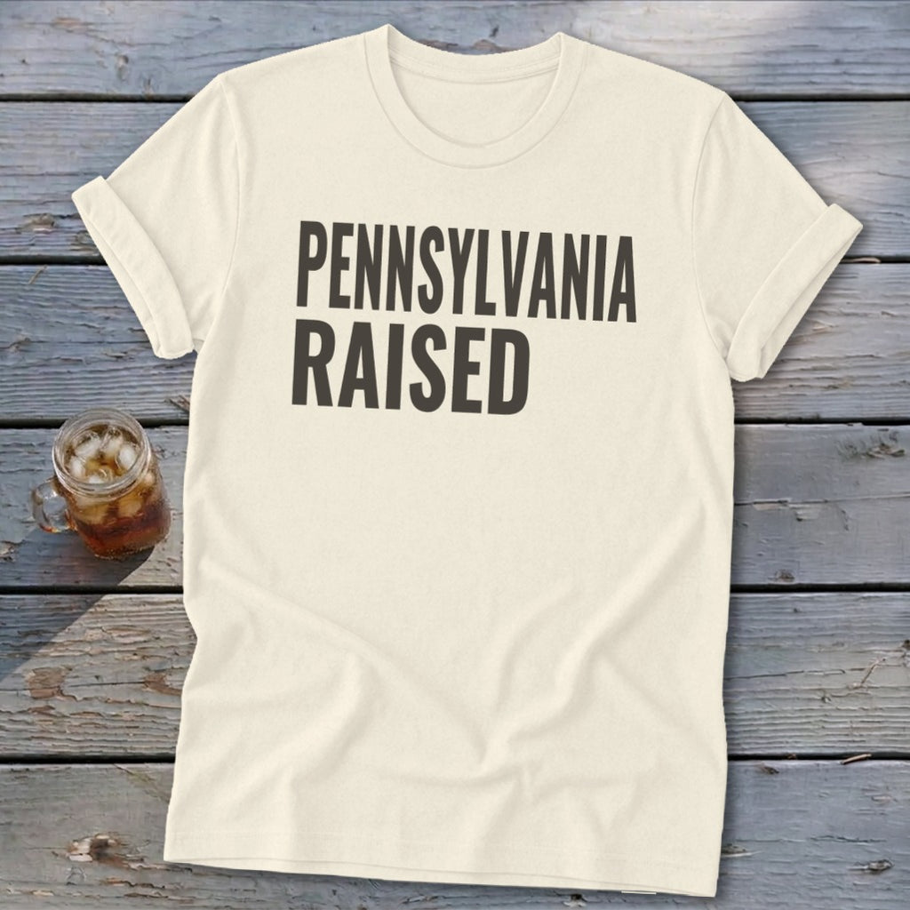 Cream t-shirt with "PENNSYLVANIA RAISED" printed in dark grey text.