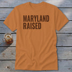 Orange t-shirt with "MARYLAND RAISED" printed in dark brown lettering.