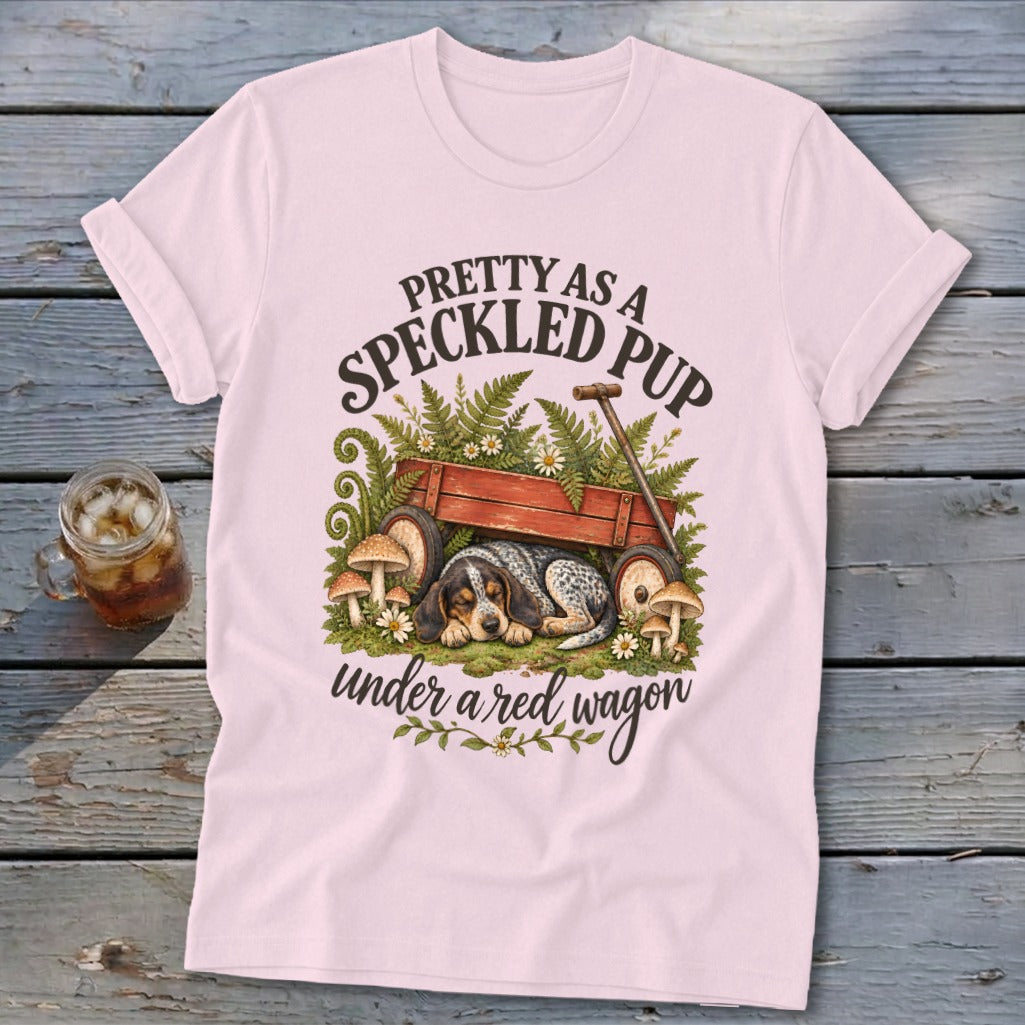 Pink t-shirt with a speckled pup sleeping under a red wagon and text.
