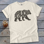 A cream-colored t-shirt with a dark brown graphic of a bear containing the word Appalachia.