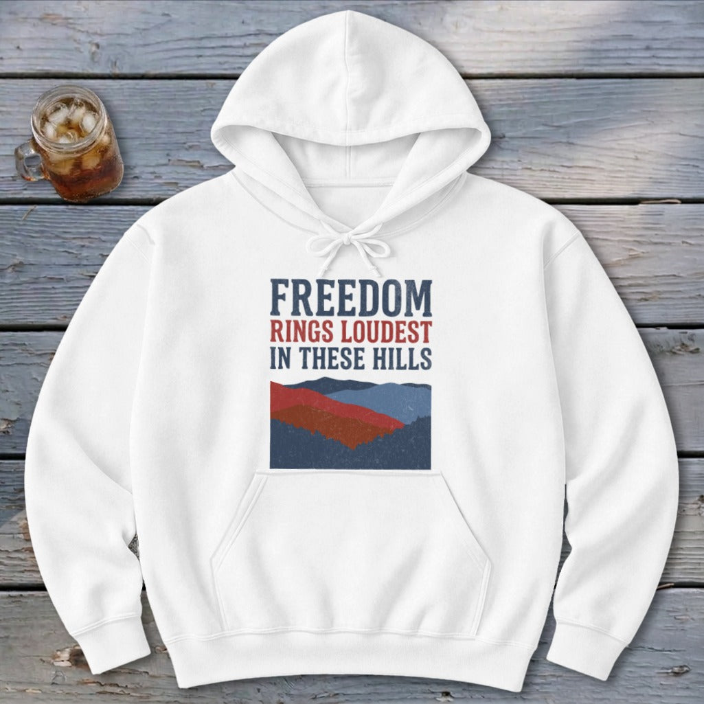White pullover hoodie featuring a graphic with mountains and the text "FREEDOM RINGS LOUDEST IN THESE HILLS."