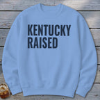 Light blue crewneck sweatshirt with "KENTUCKY RAISED" text in dark blue.