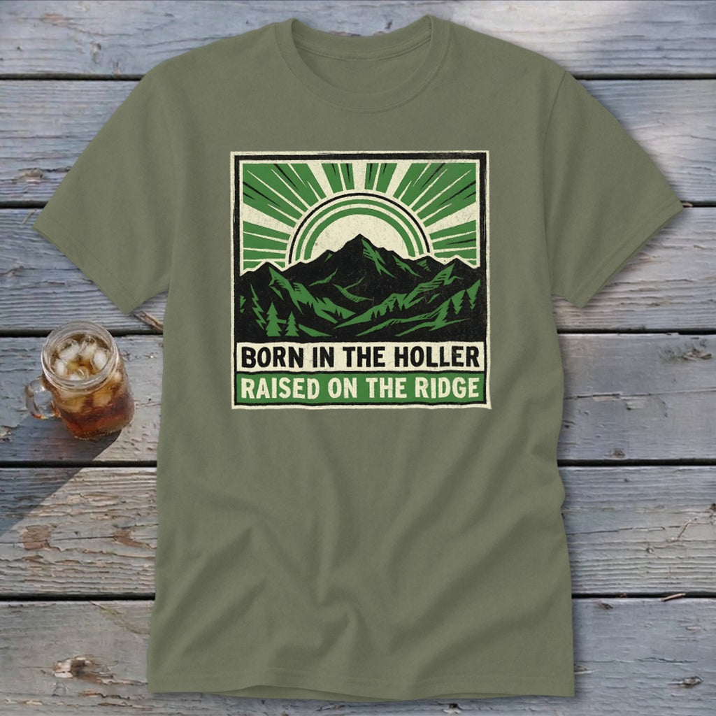 An olive green t-shirt with a vintage mountain graphic and the text Born in the Holler Raised on the Ridge.