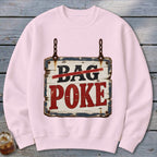 A light pink crewneck sweatshirt featuring a graphic of a rustic wooden sign that reads DAG POKE with the word DAG crossed out in red.