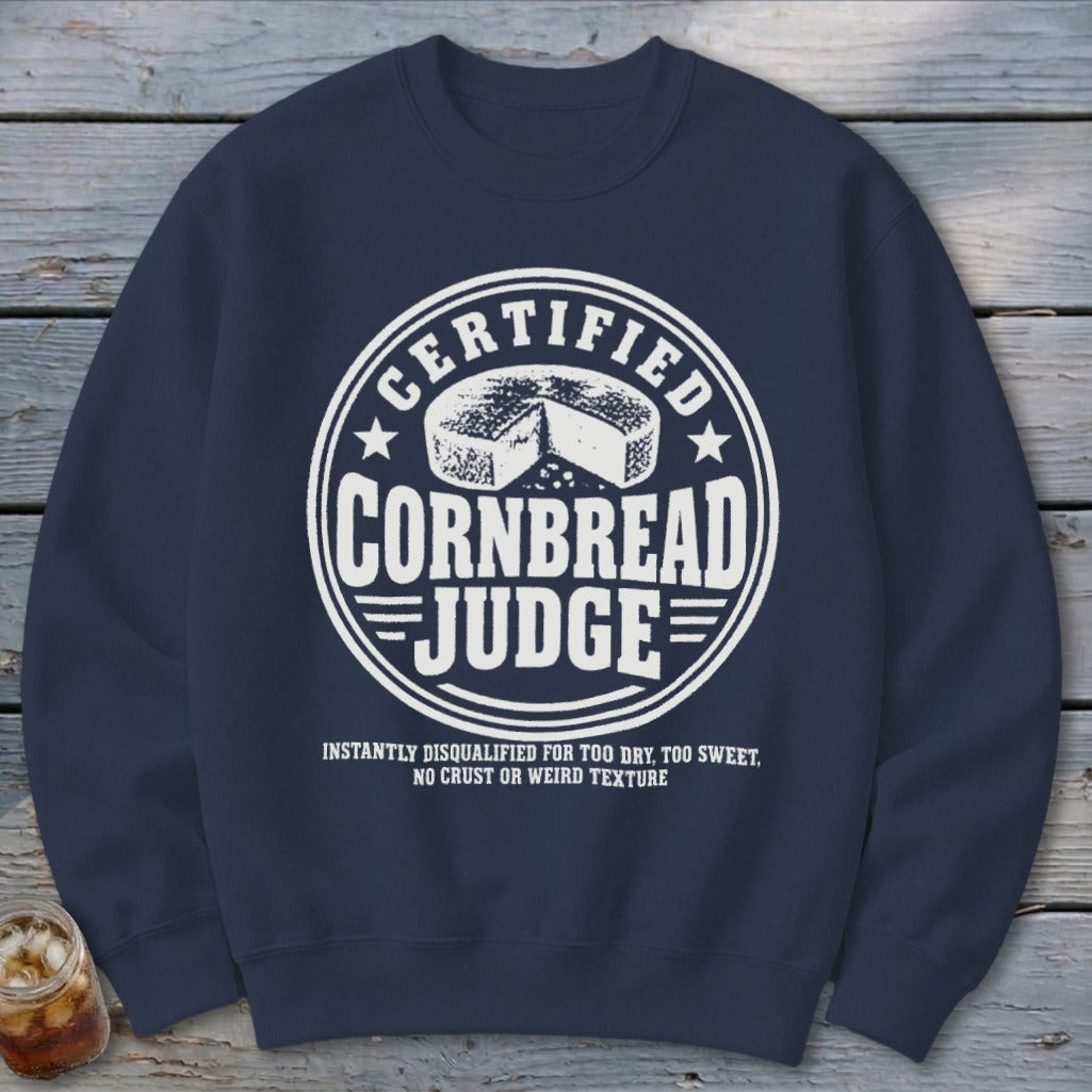 Dark blue crewneck sweatshirt featuring a white circular graphic that reads CERTIFIED CORNBREAD JUDGE.
