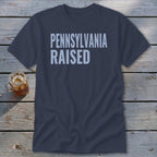 Dark navy t-shirt with "PENNSYLVANIA RAISED" printed in light blue.