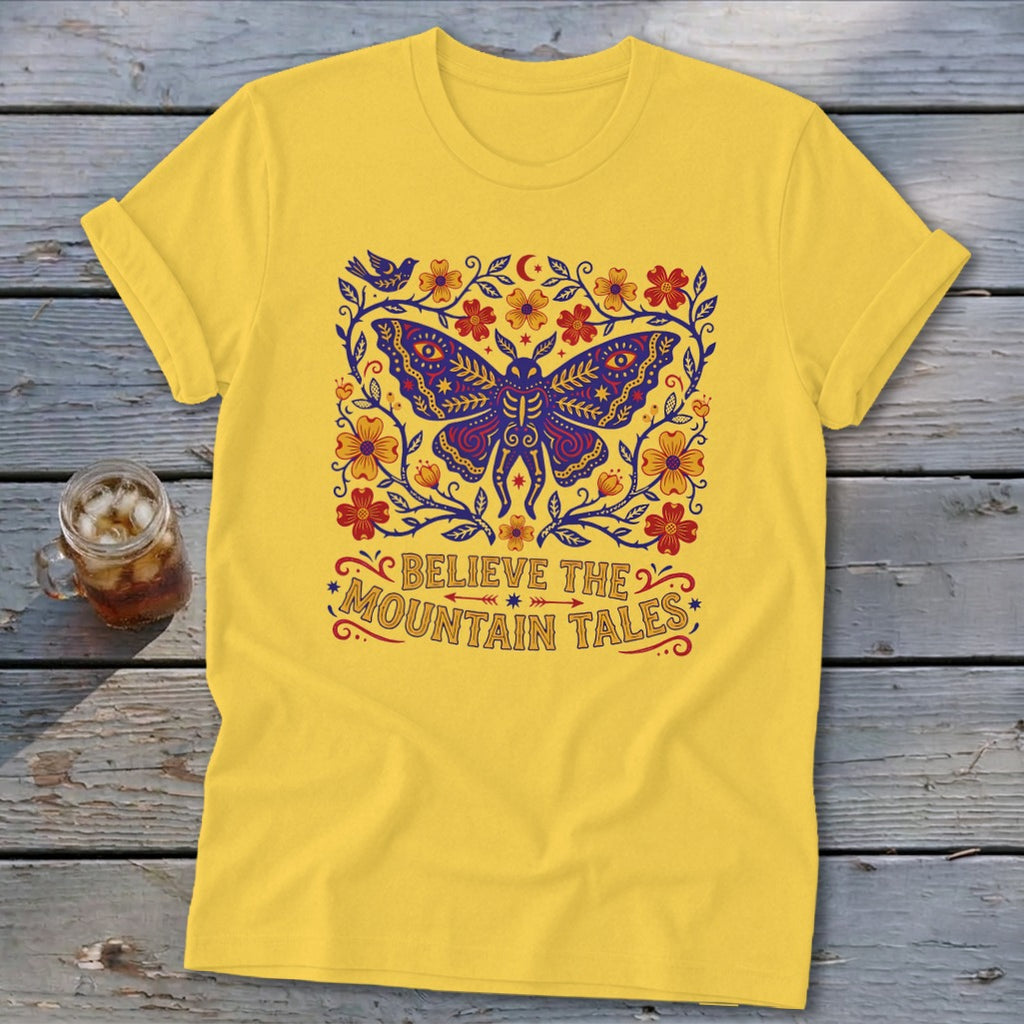 Yellow t-shirt with a blue butterfly and floral design, saying "Believe the Mountain Tales".