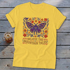 Yellow t-shirt with a blue butterfly and floral design, saying "Believe the Mountain Tales".
